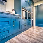Blue kitchen cabinetry with brass bar handles and integrated double ovens