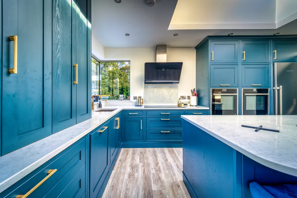 Galley view between blue kitchen island and hob run with angled extractor