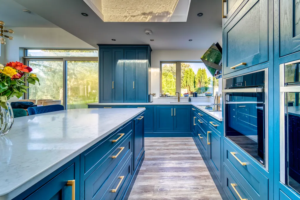Blue kitchen island beside oven wall with sliding glass doors and garden view