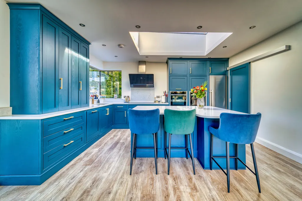 Blue kitchen with tall larder cabinets, island and velvet bar stools