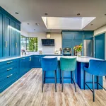 Blue kitchen with tall larder cabinets, island and velvet bar stools