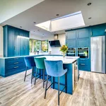 Wide view of blue kitchen with island seating and stainless steel fridge