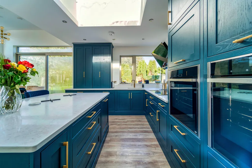 Blue shaker kitchen with brass handles and white quartz island