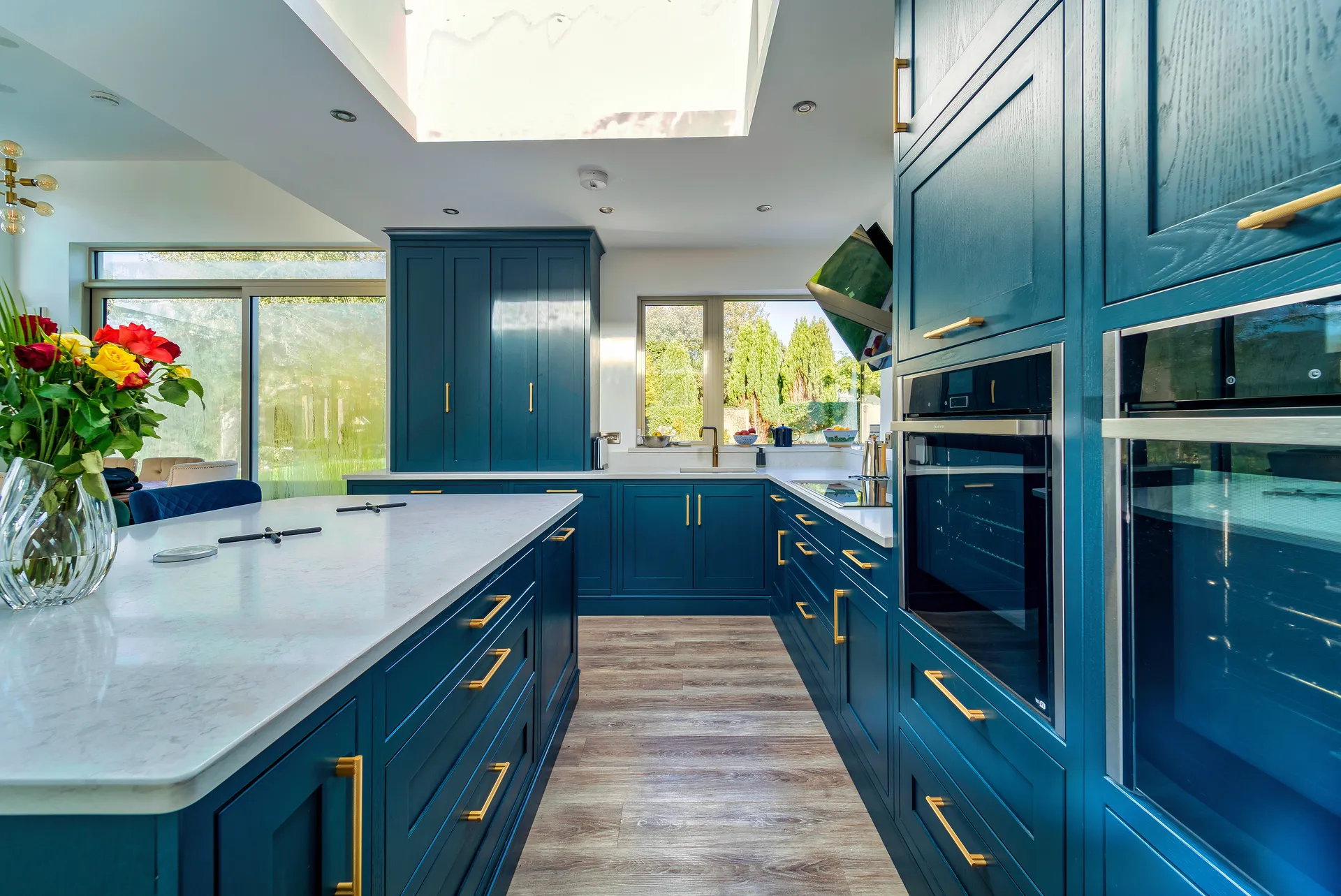 Blue shaker kitchen with brass handles and white quartz island