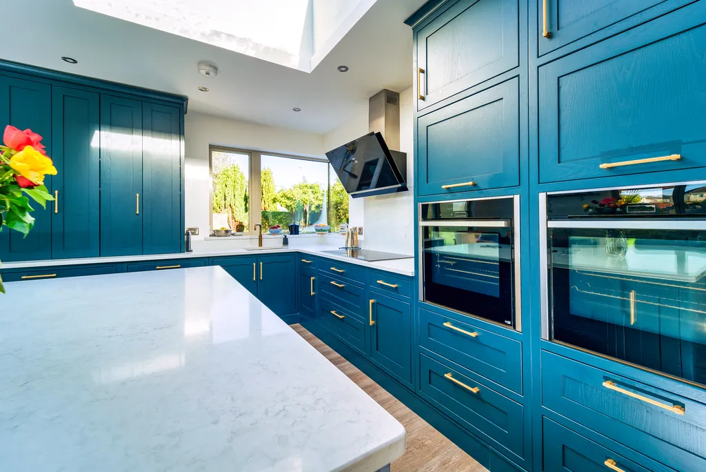 Blue shaker kitchen with white quartz island and tall oven cabinets