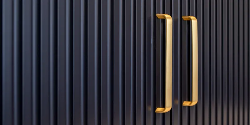 Brass bar handles on navy blue fluted cabinet doors