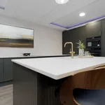 Dark green kitchen island with white quartz top and brass tap