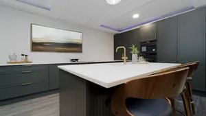 Dark green kitchen island with white quartz top and brass tap