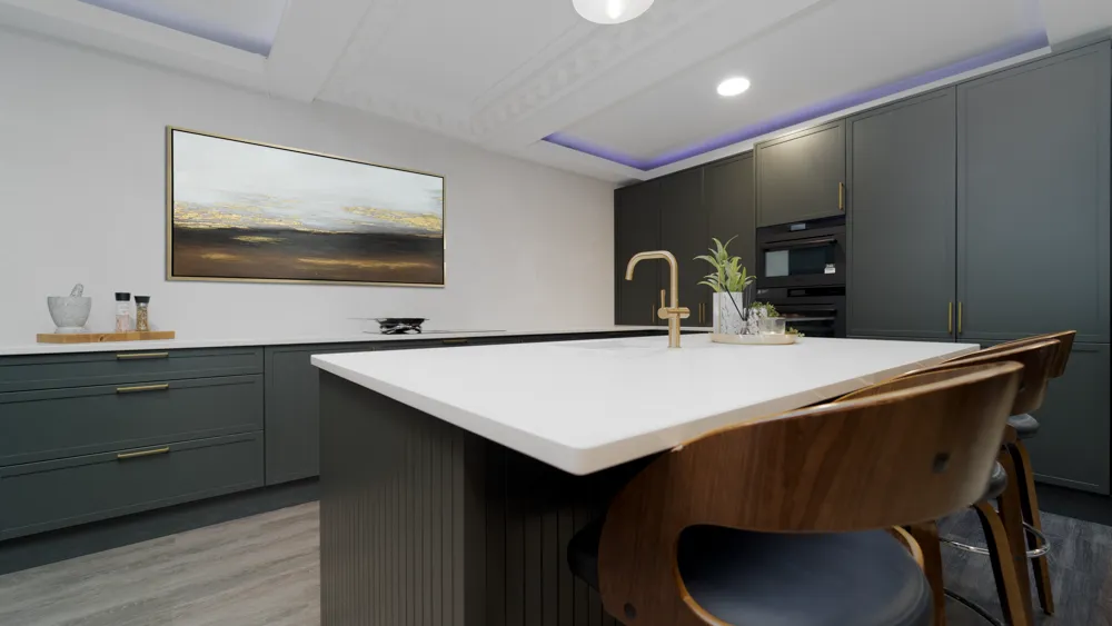 Dark green kitchen island with white quartz top and brass tap