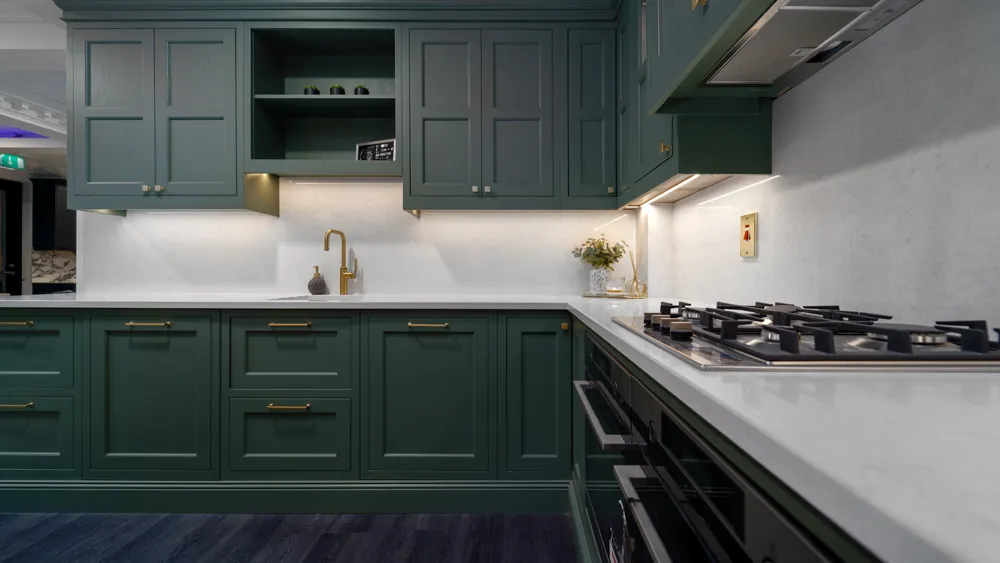 Forest green kitchen with brass tap and gas hob on quartz