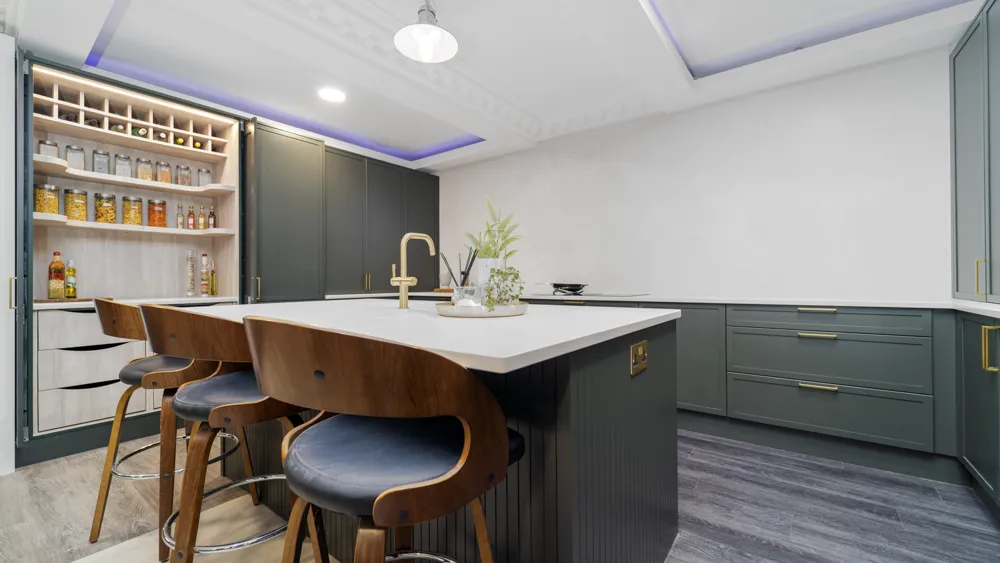 Green kitchen island with walnut bar stools and open pantry