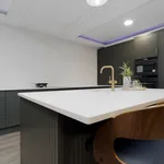 Dark green kitchen island with brass tap and gold framed artwork