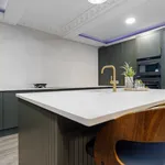 Dark green shaker kitchen with island, tall units and walnut stools