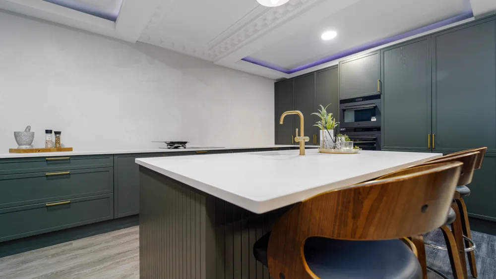 Dark green shaker kitchen with island, tall units and walnut stools
