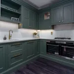 Wide view of green shaker kitchen with double ovens and hob