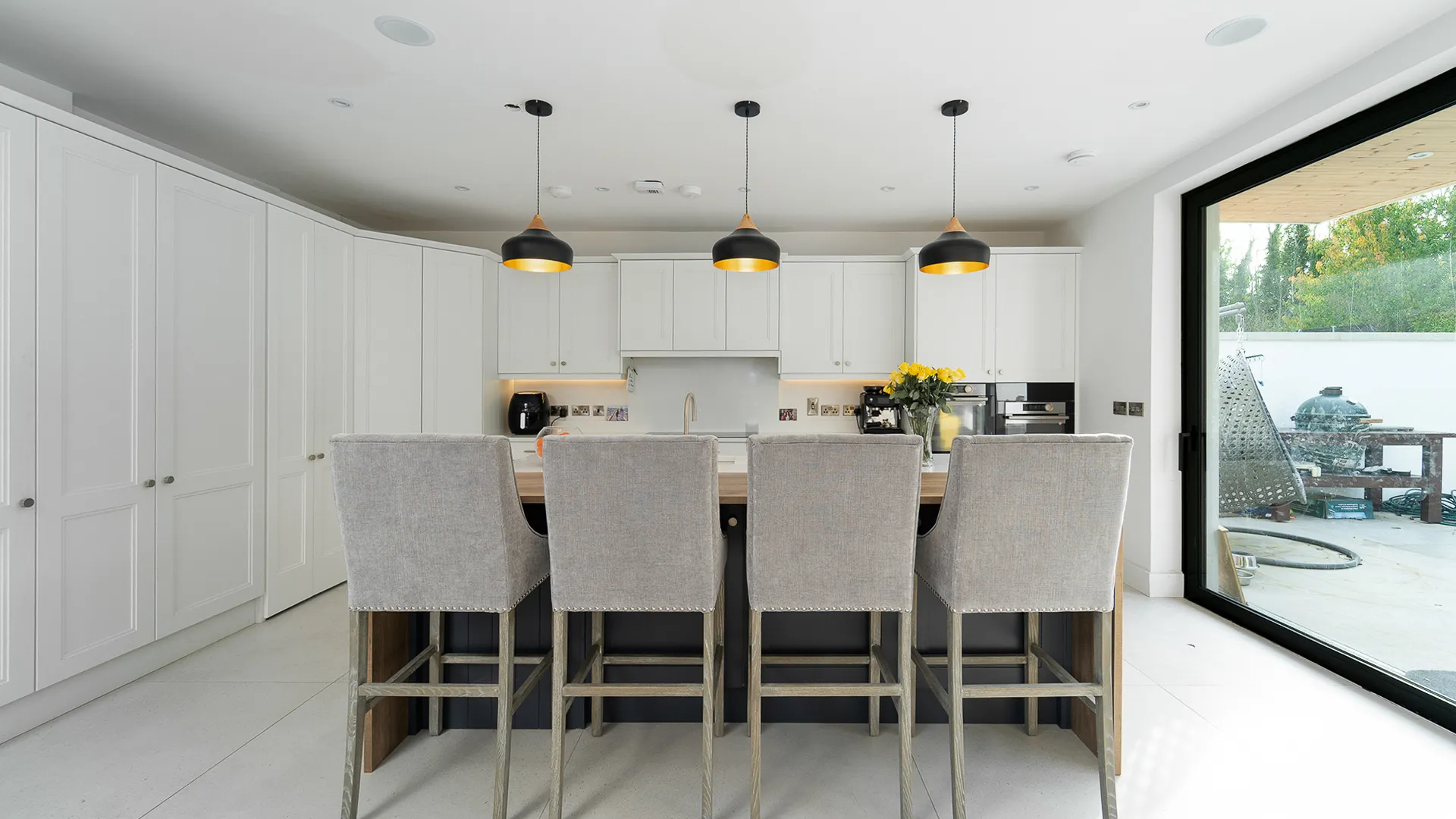 Four grey upholstered bar stools at an island breakfast bar
