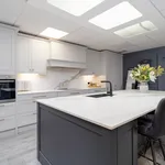 Grey kitchen with dark island, black tap and leather stools