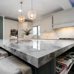 Marble effect quartz island with grey velvet stools and pendant lights