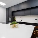 Matt black kitchen with white quartz island and walnut bar stools