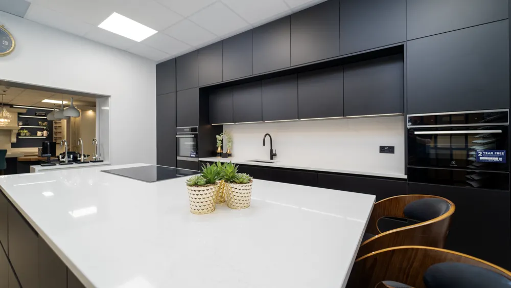 Matt black kitchen with white quartz island and walnut bar stools
