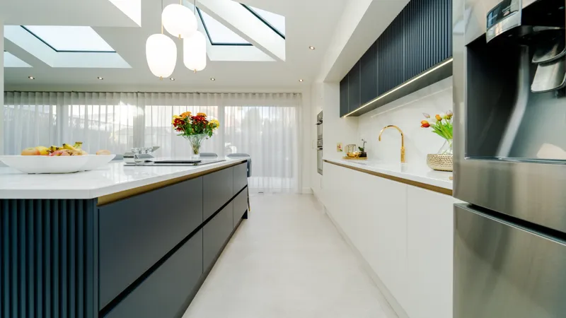 Modern galley kitchen with navy island, white cabinets and skylights