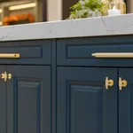 Navy blue cabinet doors with brass handles under marble worktop