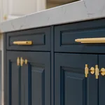 Angled detail of brass knurled handles on navy blue doors