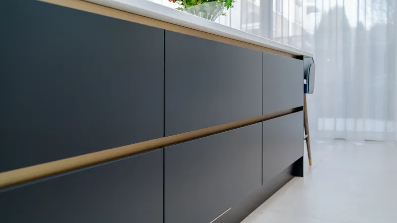 Navy handleless kitchen drawers with brushed brass trim rails