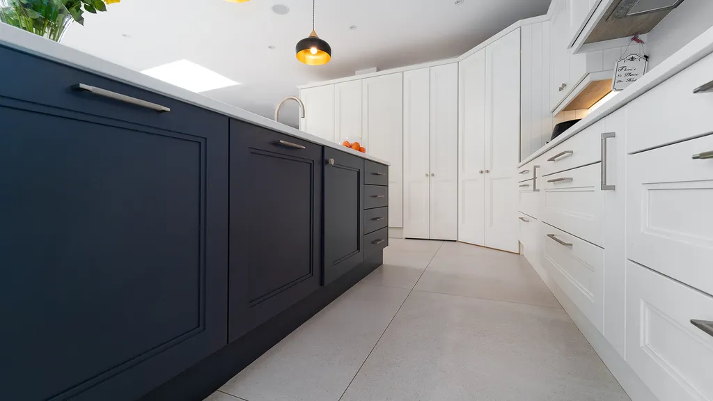 Low angle view along navy island facing white shaker cabinets