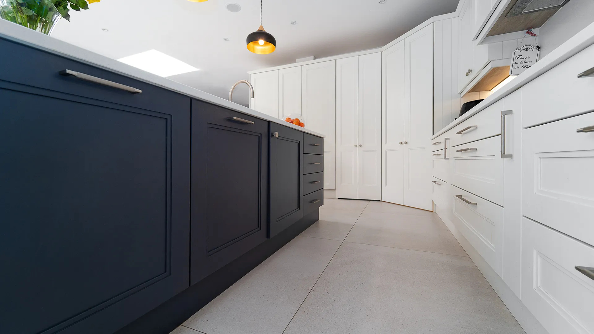 Low angle view along navy island facing white shaker cabinets
