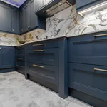 Navy shaker kitchen with gold veined marble splashback and brass handles