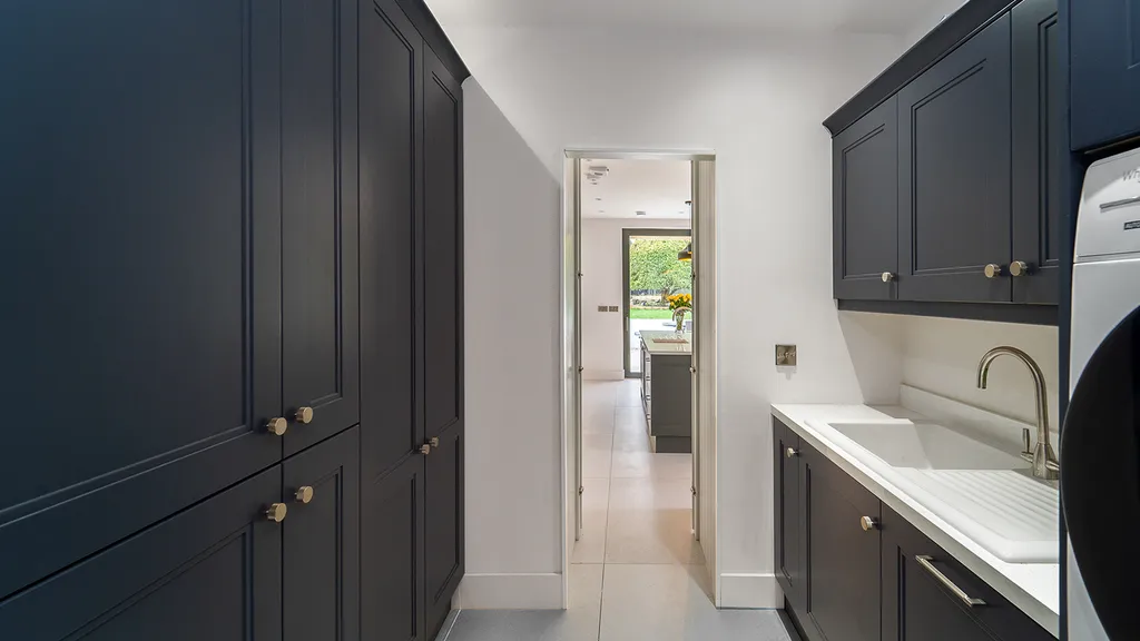 Navy blue shaker utility room with tall cabinets and white sink