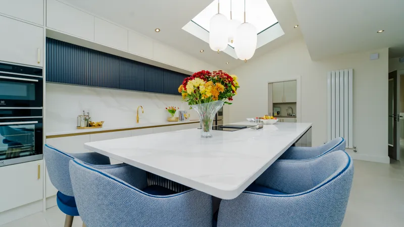 White quartz kitchen island with dining seating and blue upholstered chairs