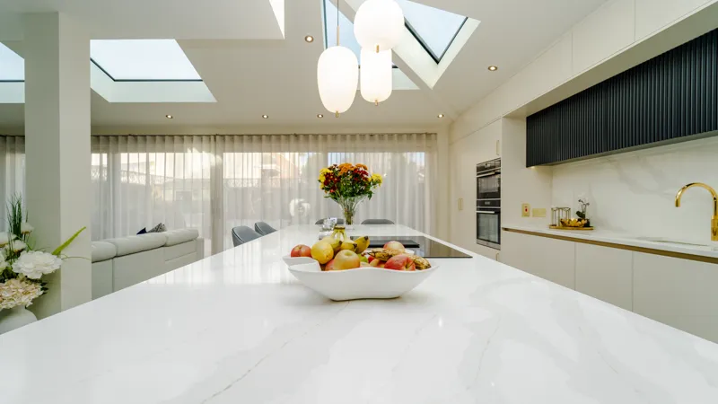 White quartz island worktop with fruit bowl in bright open plan kitchen
