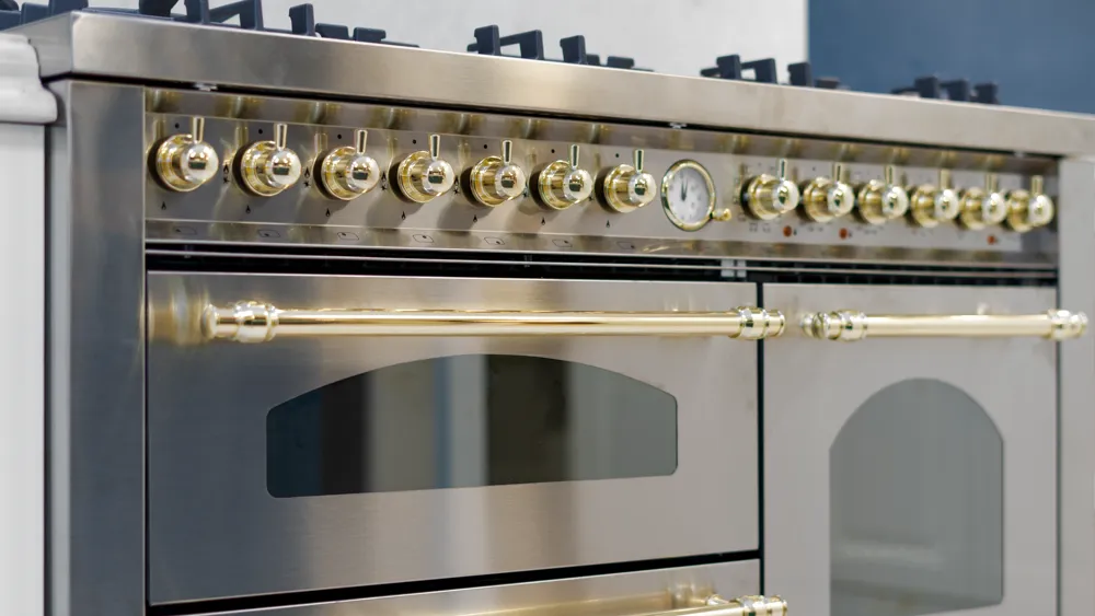Stainless steel range cooker with polished brass knobs and rail handles