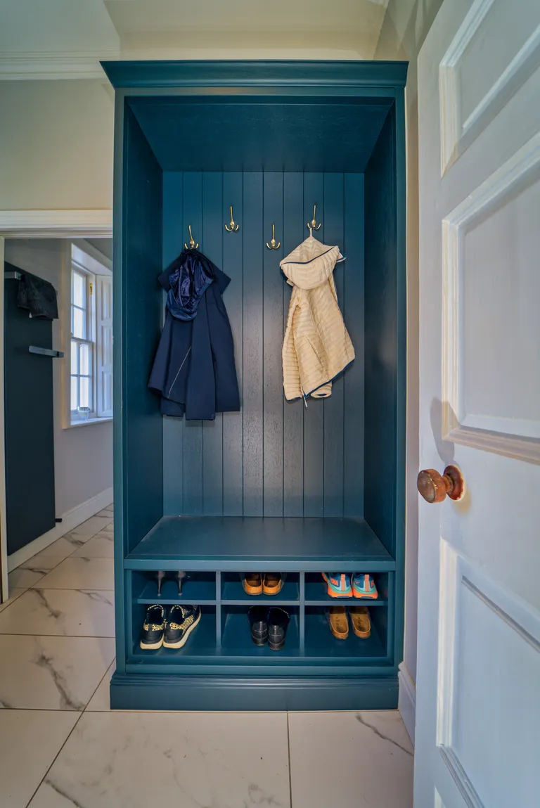 Teal built in hallway unit with coat hooks, bench and shoe storage