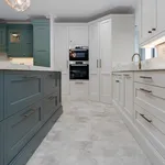 Two tone kitchen with teal island, green and cream cabinets