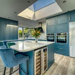 Teal kitchen with tall larders, stainless fridge and island wine cooler