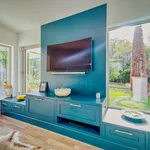 Teal television unit flanked by windows with garden views