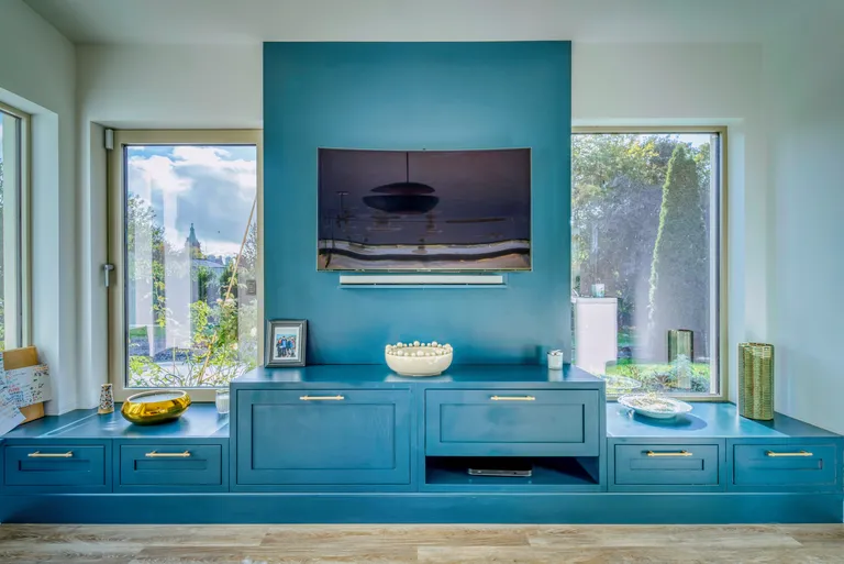 Symmetrical view of teal media wall with centred television