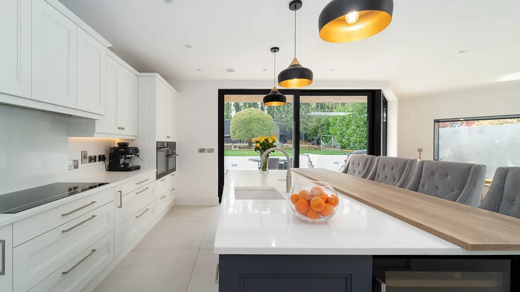 Two tone kitchen with white quartz island and oak breakfast bar