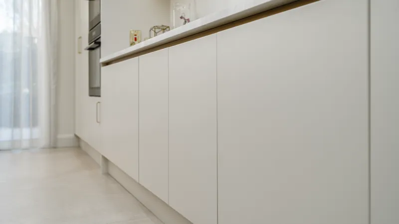 White handleless kitchen base cabinets beneath a marble effect worktop