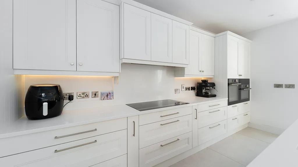 White kitchen run with induction hob and integrated double ovens