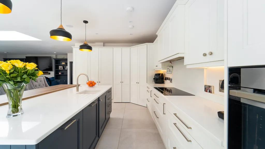 White kitchen with navy island looking towards the corner pantry