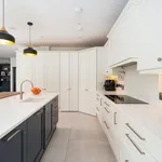 White kitchen with navy island looking towards the corner pantry