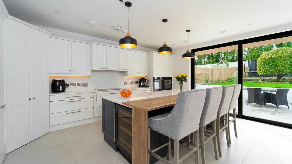 Open plan white kitchen with navy island and garden sliding doors