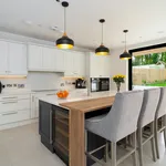 Open plan white kitchen with navy island and garden sliding doors