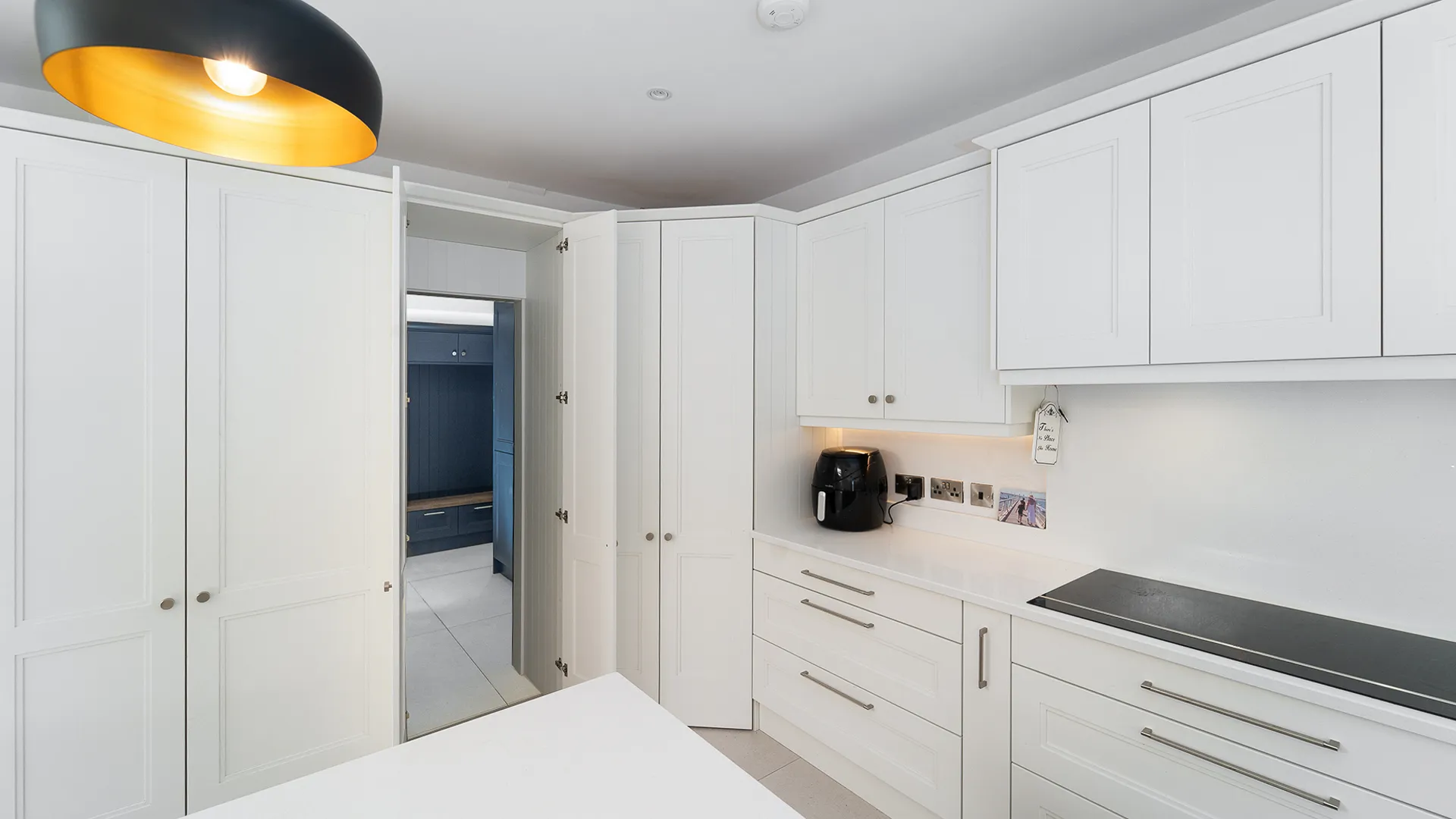 White shaker kitchen corner larder beside door to navy boot room