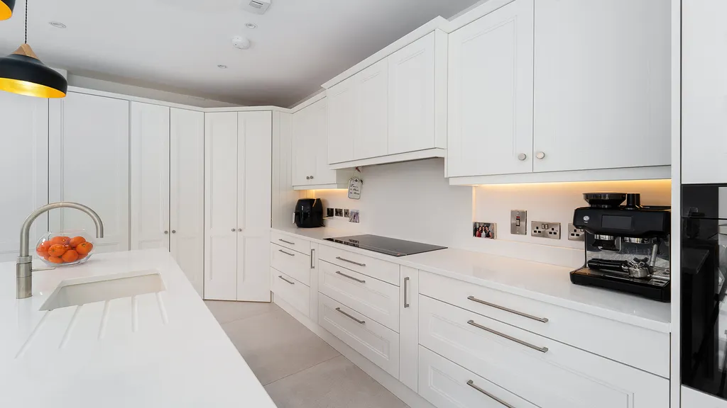 White shaker kitchen with corner larder, induction hob and coffee machine