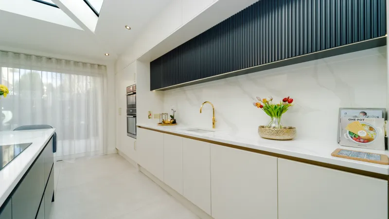 White handleless sink run with brass tap and navy fluted wall units